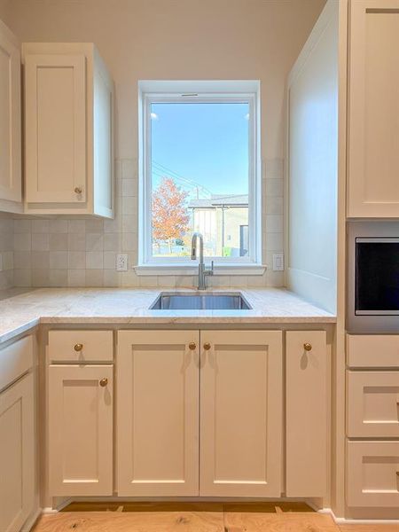 Kitchen workspace featuring a stainless steel undermount sink, gooseneck faucet, light-toned countertops, and a subway tile backsplash