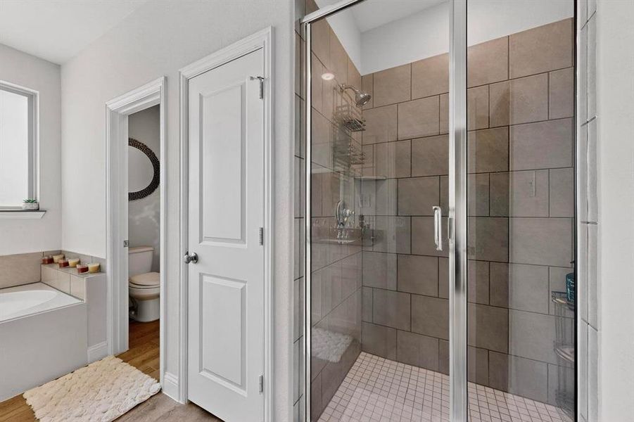 Full bath with a shower stall, a bath, and light wood-type flooring Full bath with a shower stall, a bath, and light wood-type flooring