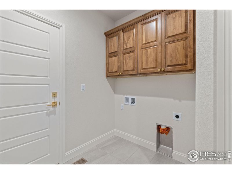 On the other wall of the mudroom are the washer/dryer hookups with soft close overhead cabinets above