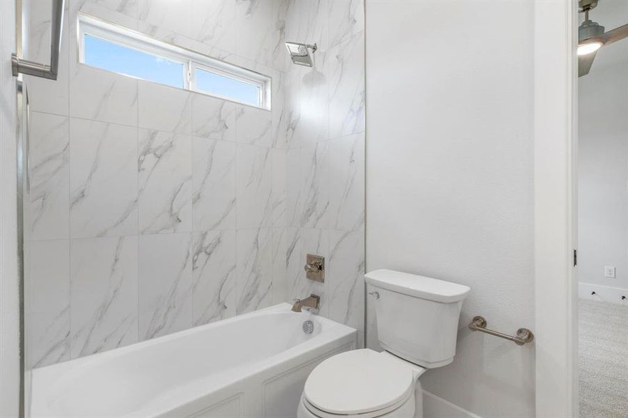 Bathroom with tiled shower / bath combo and toilet