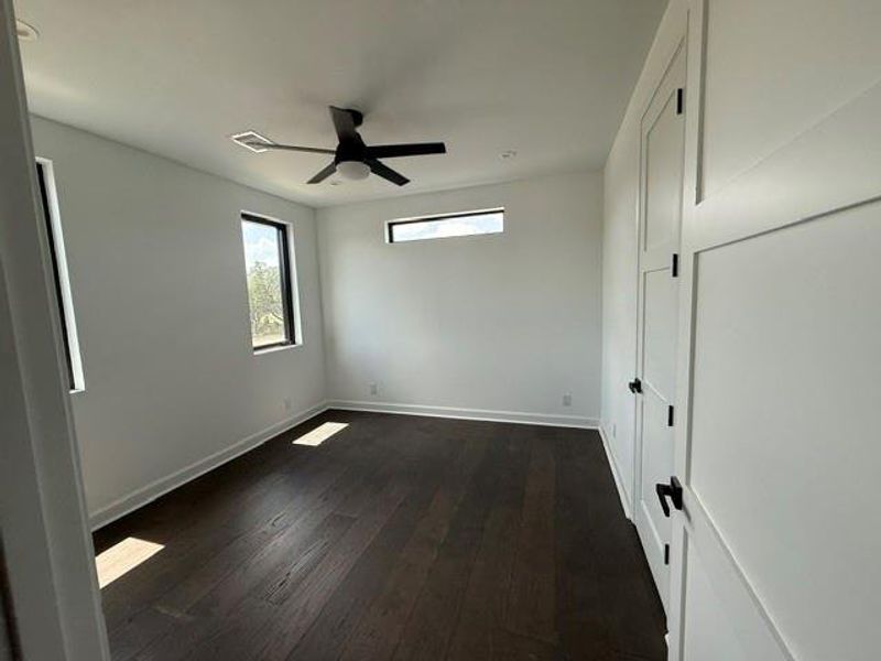Bright and airy upstairs bedroom featuring sleek hardwood floors and modern fixtures.