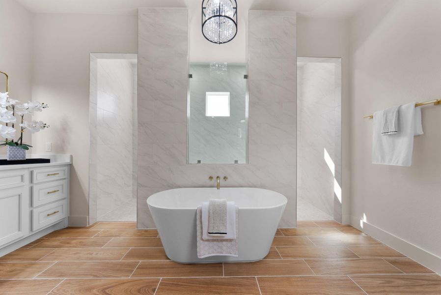 A deep soaking tub forms the centerpiece of this primary bath with elegant tile accents and modern fixtures.
