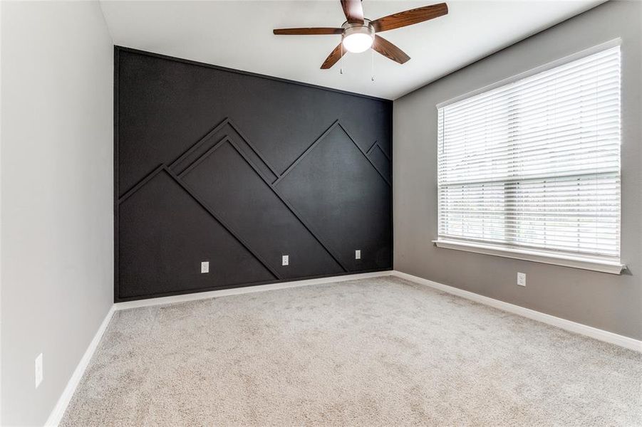 Unfurnished room featuring ceiling fan, carpet flooring, and a wealth of natural light