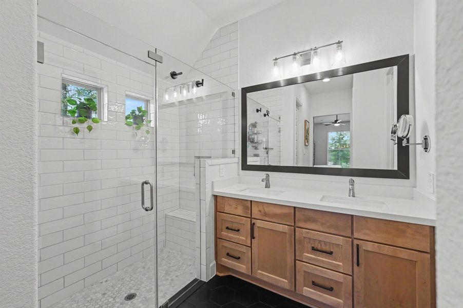 There is a large walk-in shower with floor-to-ceiling subway tile surround and a bench seat. The frameless shower enclosure was upgraded after move-in. The two small windows bring natural light in the space. There is a large walk-in shower with floor-to-ceiling subway tile surround and a bench seat. The frameless shower enclosure was upgraded after move-in. The two small windows bring natural light in the space.