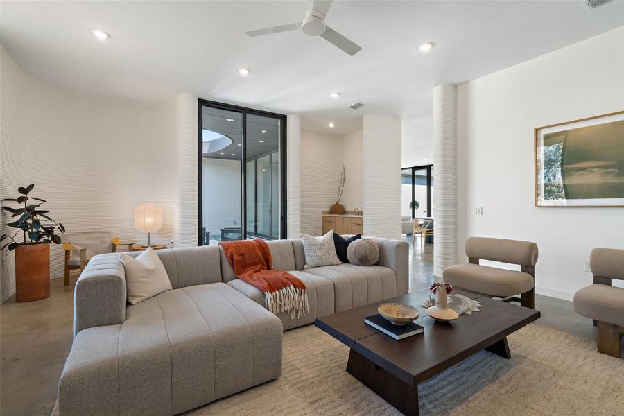 Living room featuring ceiling fan and a wall of windows