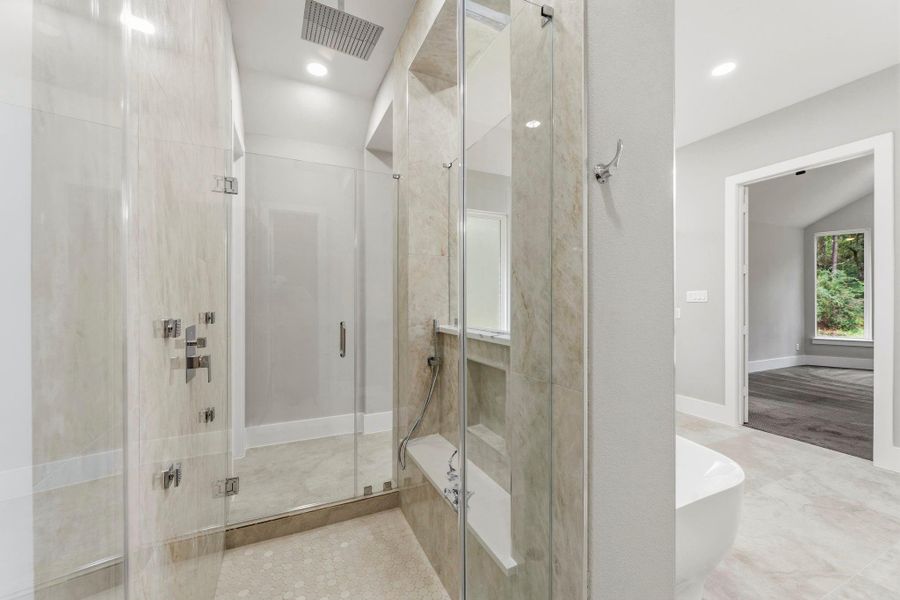 The oversized walk-in shower creates a true spa experience with dual glass entry doors, floor to ceiling stonework, and multiple shower fixtures. A private retreat designed to make everyday feel indulgent.