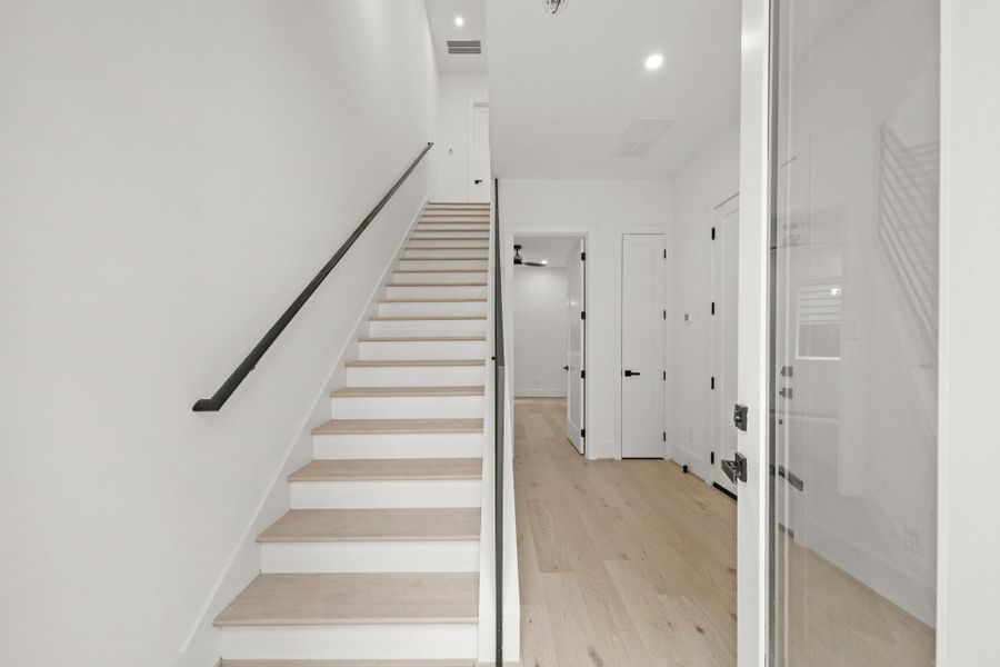 The spacious foyer of the Charleston plan includes recessed lighting, gorgeous hardwood flooring, high ceilings, a nook to the right for accent furniture, entry to the first floor bedroom with ensuite bath, access to the home’s two car attached garage and a coat closet. The staircase has hardwood treads with modern wrought iron spindles leading to the second level of the home.