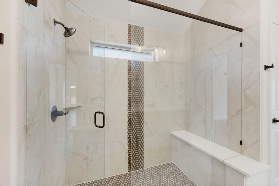 Walk-in shower with marble-look tile walls, glass doors, built-in bench, and hexagon mosaic tile accents
