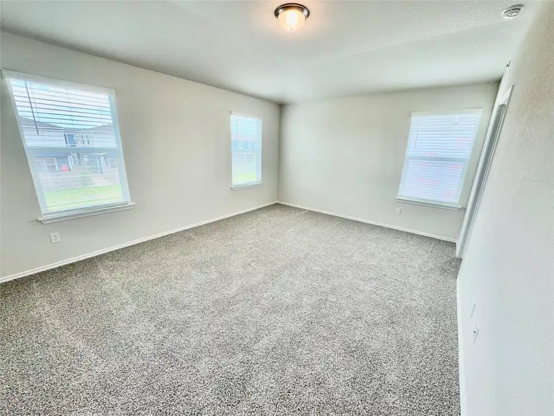 Empty room with healthy amount of natural light, carpet flooring, and a textured ceiling