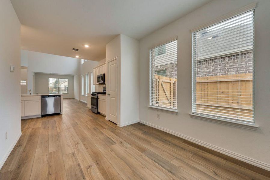 Kitchen with light hardwood / wood-style flooring, appliances with stainless steel finishes, sink, white cabinetry, and lofted ceiling