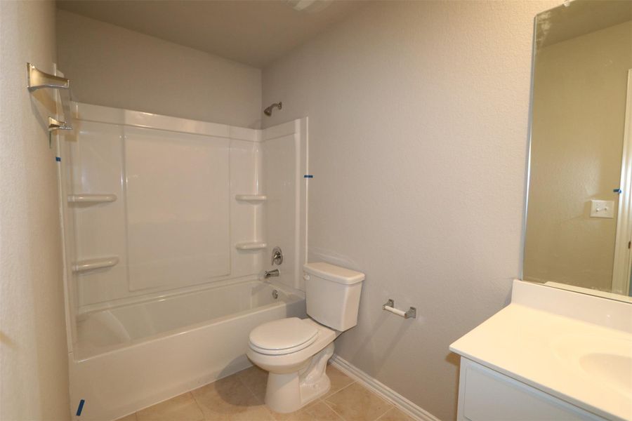 Full bathroom featuring toilet, washtub / shower combination, tile patterned floors, and vanity