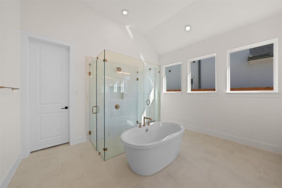 Full bath featuring a freestanding bath, a shower stall, lofted ceiling, light tile patterned flooring, and recessed lighting Full bath featuring a freestanding bath, a shower stall, lofted ceiling, light tile patterned flooring, and recessed lighting
