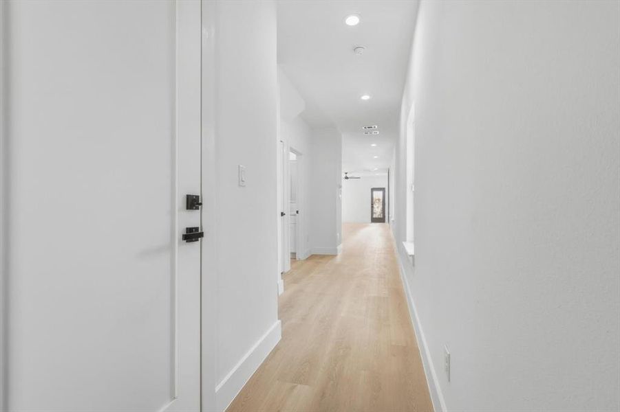Hallway with light wood finished floors and recessed lighting