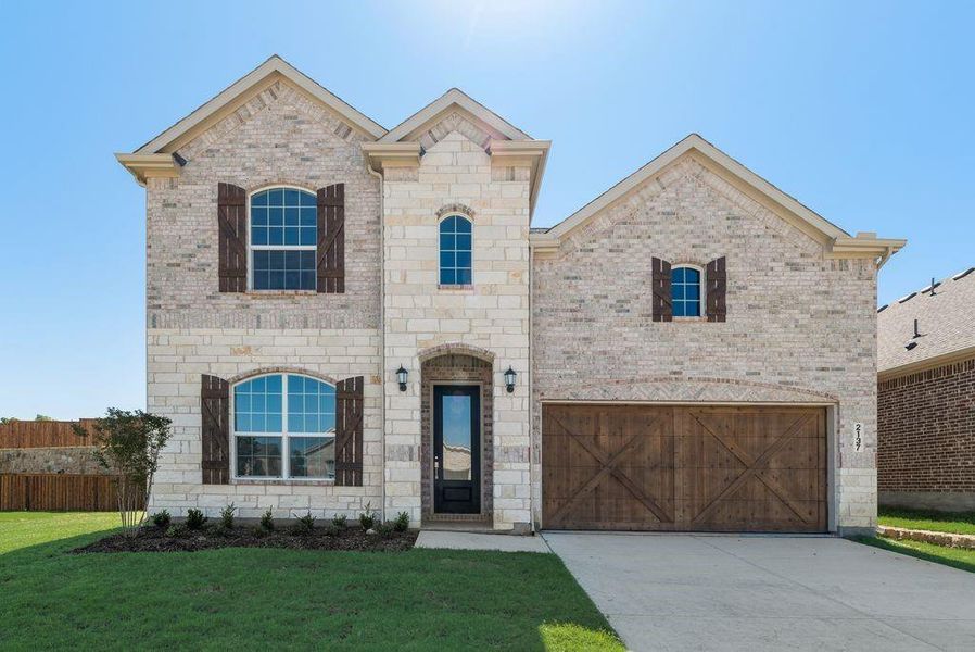 French country style house with a garage, stone siding, brick siding, and driveway