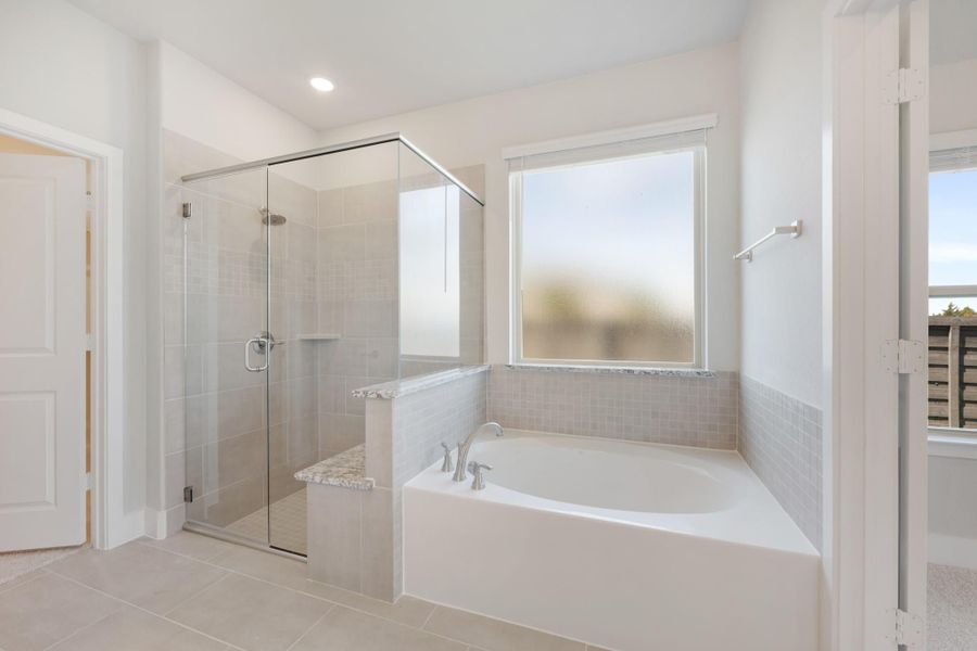 Master bathroom with soaking tub, glass-enclosed walk-in shower, and neutral tile walls and floors Master bathroom with soaking tub, glass-enclosed walk-in shower, and neutral tile walls and floors
