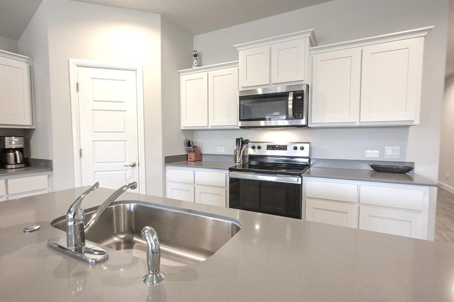 Kitchen featuring appliances with stainless steel finishes, white cabinetry, and a sink