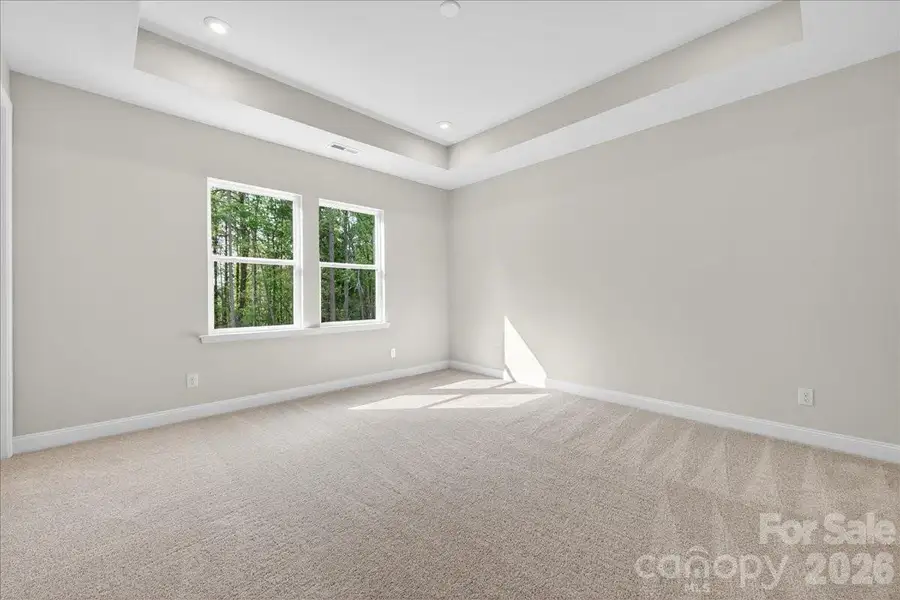 Light filled primary bedroom with tray ceiling