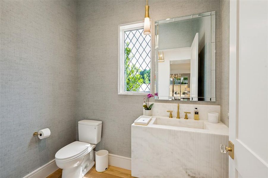 Powder room featuring a white marble vanity with integrated sink, brass-finish faucet, and an ornate framed mirror