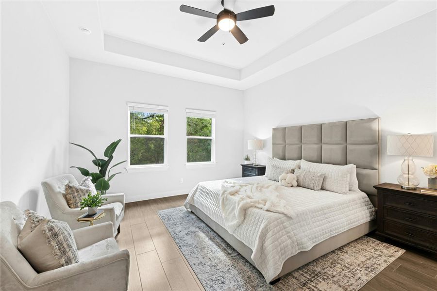 Bedroom featuring a raised ceiling, wood finished floors, and ceiling fan Bedroom featuring a raised ceiling, wood finished floors, and ceiling fan