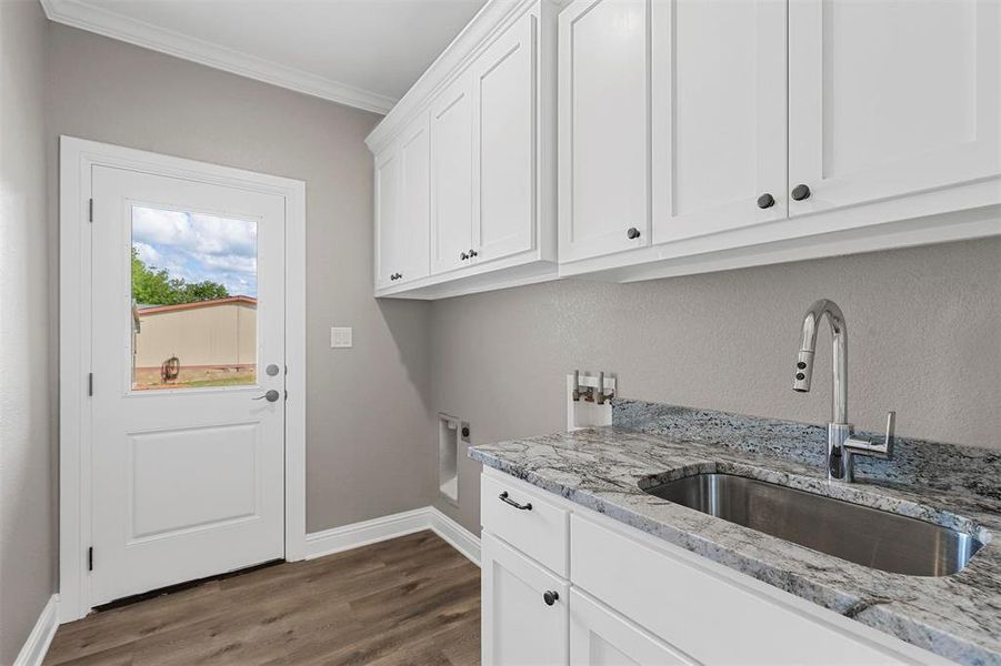 Laundry room with crown molding, sink, hookup for a washing machine, dark hardwood / wood-style floors, and cabinets