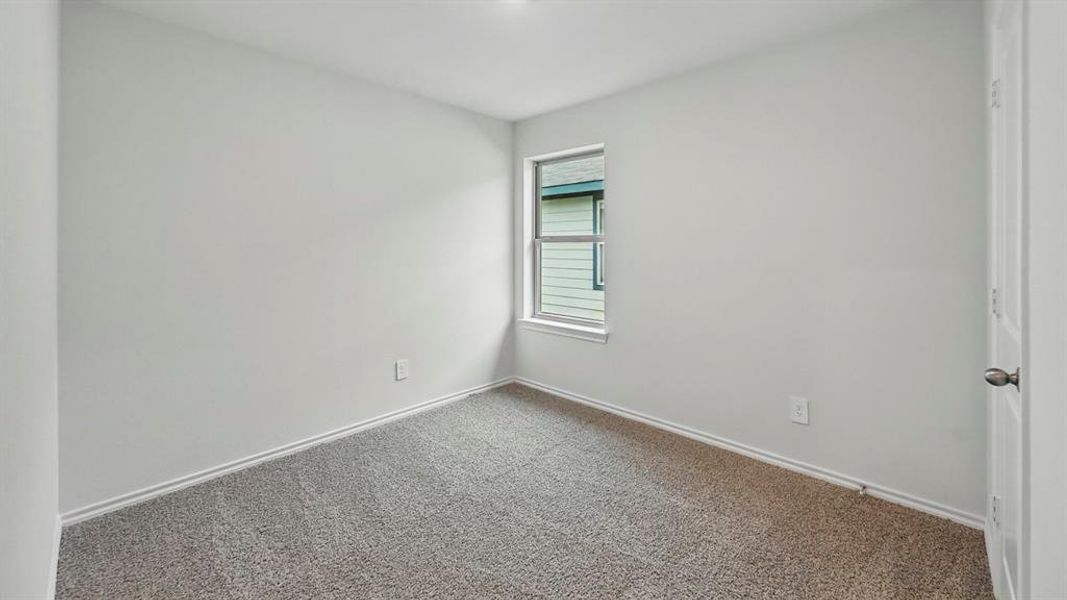 This room features light-colored walls, carpet flooring, a window providing natural light, and a white door with a round knob