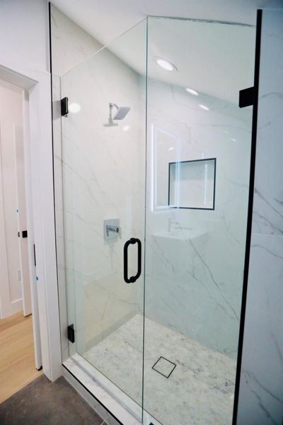 Full bath with a marble finish shower
