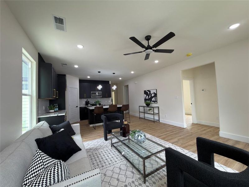 Open-concept living area with wood-finish flooring, recessed lighting, and a contemporary ceiling fan