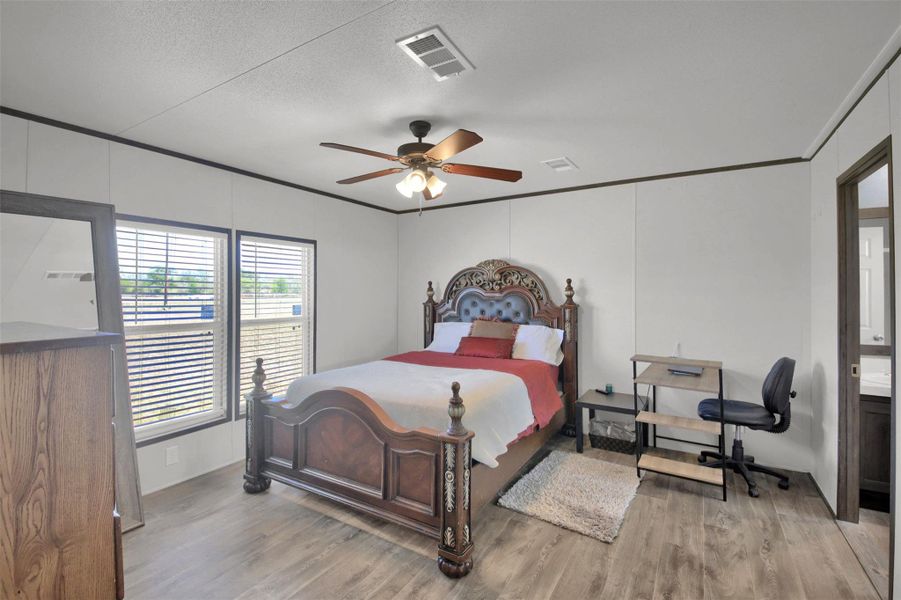 Bedroom with a ceiling fan, crown molding, wood finished floors, and ensuite bath