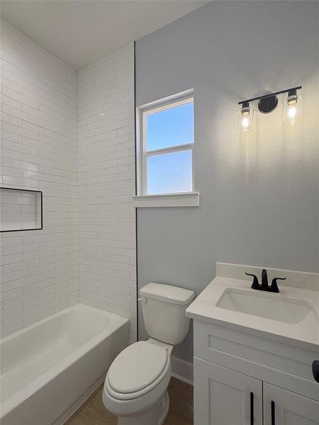 A beautifully upscale bathroom featuring a modern subway tile shower  with black fixtures, and bright natural light streaming through the window for a fresh and inviting ambiance.