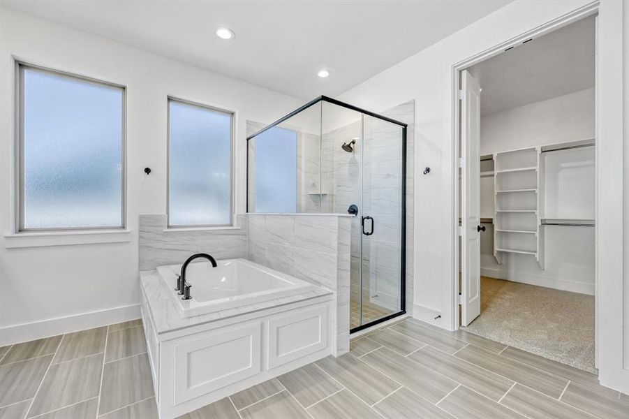 Bathroom with a walk in closet, a stall shower, a bath, and recessed lighting