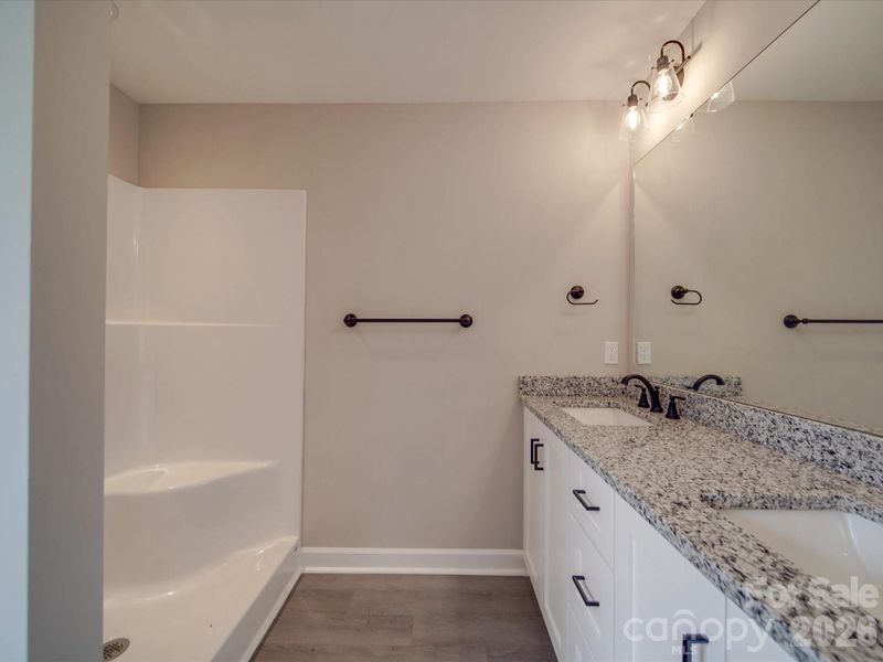 Primary bath with dual vanities, granite countertops, and upgraded accent lighting.