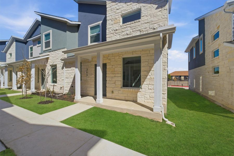 View of front of house featuring covered porch, a front lawn, stone siding, and stucco siding