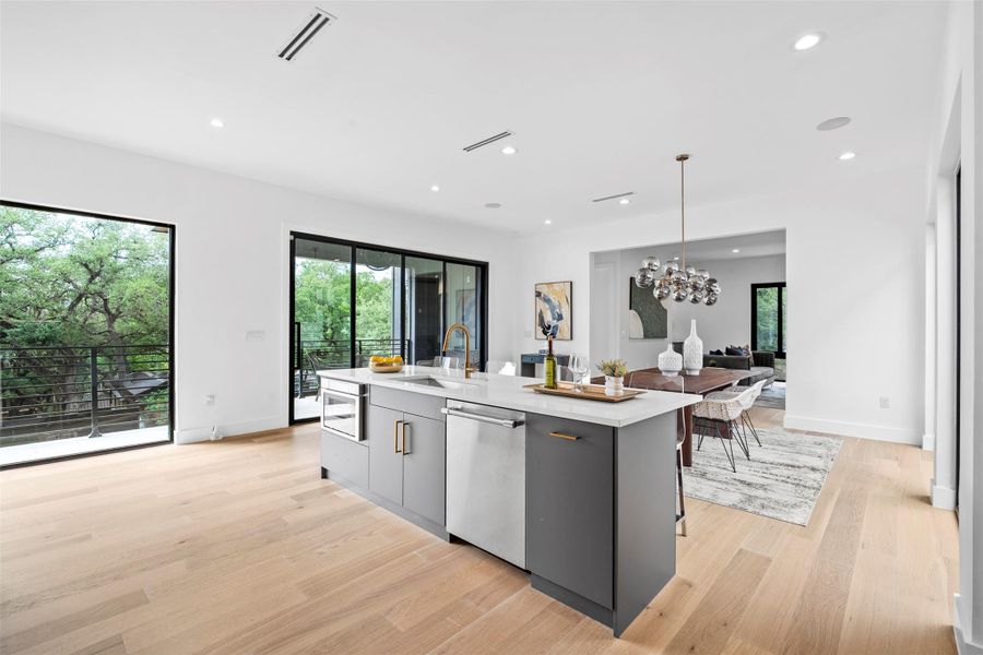 The property features a kitchen with a central island, light wood flooring, and white walls