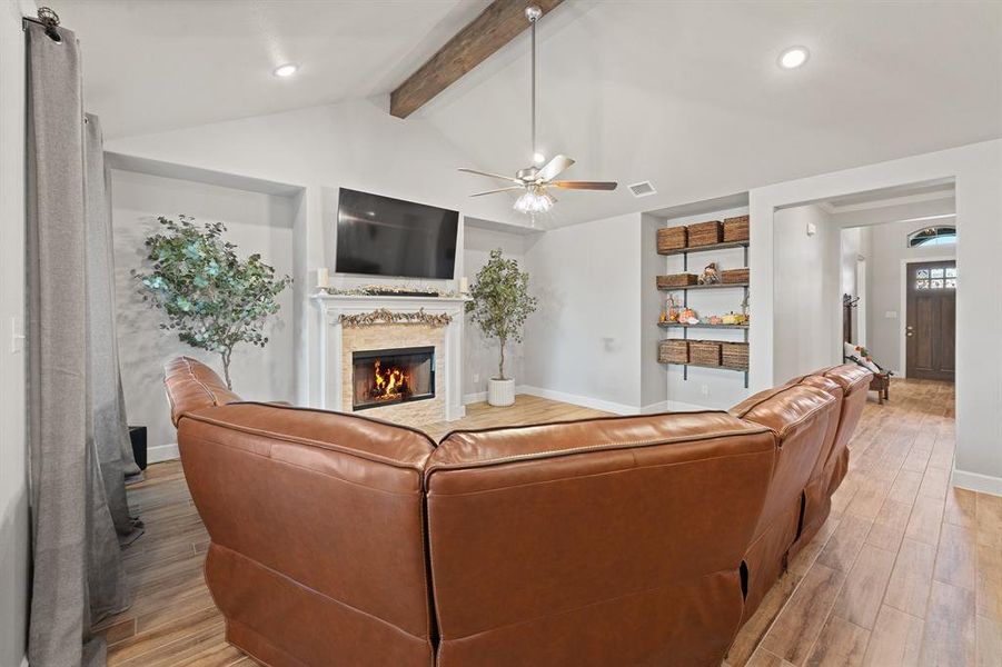 Living room with light wood-style floors, a glass covered fireplace, recessed lighting, and a ceiling fan