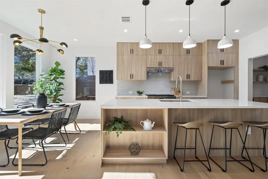 Kitchen with an island with sink, sink, backsplash, a kitchen breakfast bar, and light hardwood / wood-style flooring