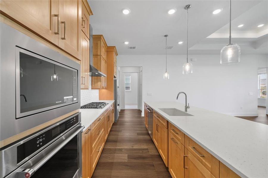 Gourmet kitchen featuring a built-in stainless steel microwave and oven, a gas cooktop with a range hood, and a white subway tile backsplash