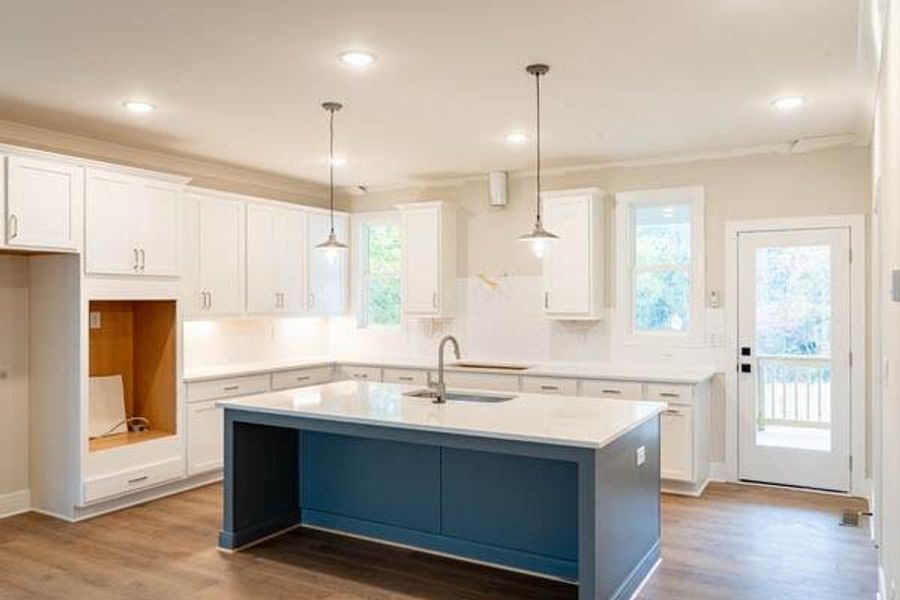 Kitchen featuring an island with sink, white cabinets, and hardwood / wood-style floors Kitchen featuring an island with sink, white cabinets, and hardwood / wood-style floors