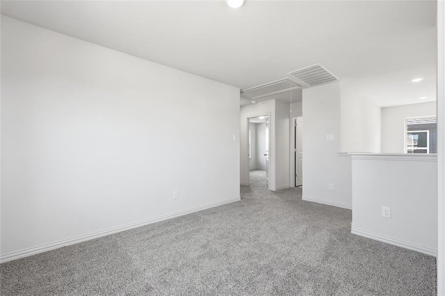 Spacious room featuring light gray carpeting, white walls, white baseboards, and overhead lighting
