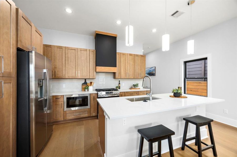 This stunning kitchen has plenty of storage, complemented by a stylish vent hood that adds a modern touch, along with a cleverly hidden microwave built into the lower cabinetry for a seamless look.