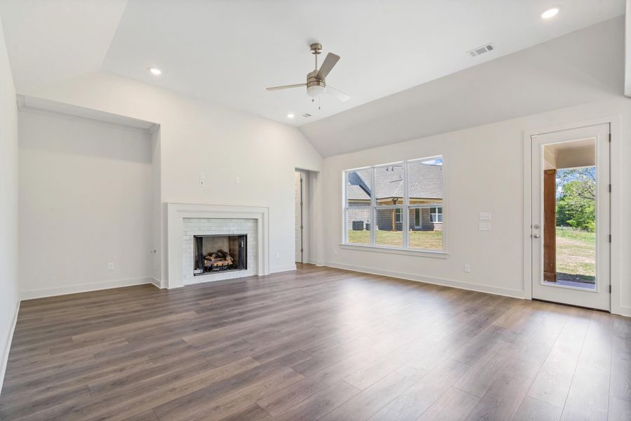 Unfurnished living room with ceiling fan, recessed lighting, vaulted ceiling, dark wood finished floors, and a fireplace