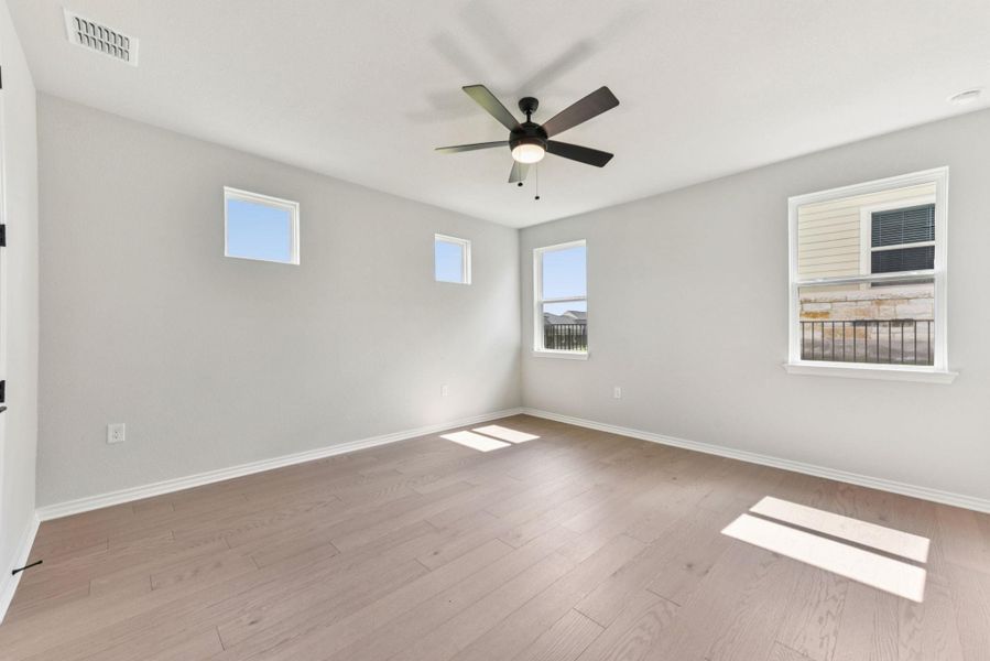 Unfurnished room with light wood finished floors, healthy amount of natural light, and ceiling fan