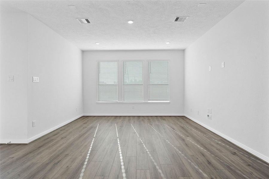 Bring family and friends together in this beautiful family room! It features soaring ceilings, recessed lighting, custom paint, stunning flooring, and large windows fitted with blinds - which will fill the space with natural light all day long.