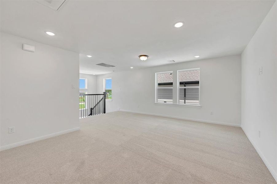 Spacious upper-level room with neutral carpeting and white painted walls