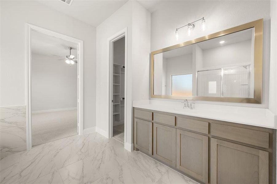 Bathroom featuring marble finish flooring, vanity, ceiling fan, a walk in closet, and a shower Bathroom featuring marble finish flooring, vanity, ceiling fan, a walk in closet, and a shower