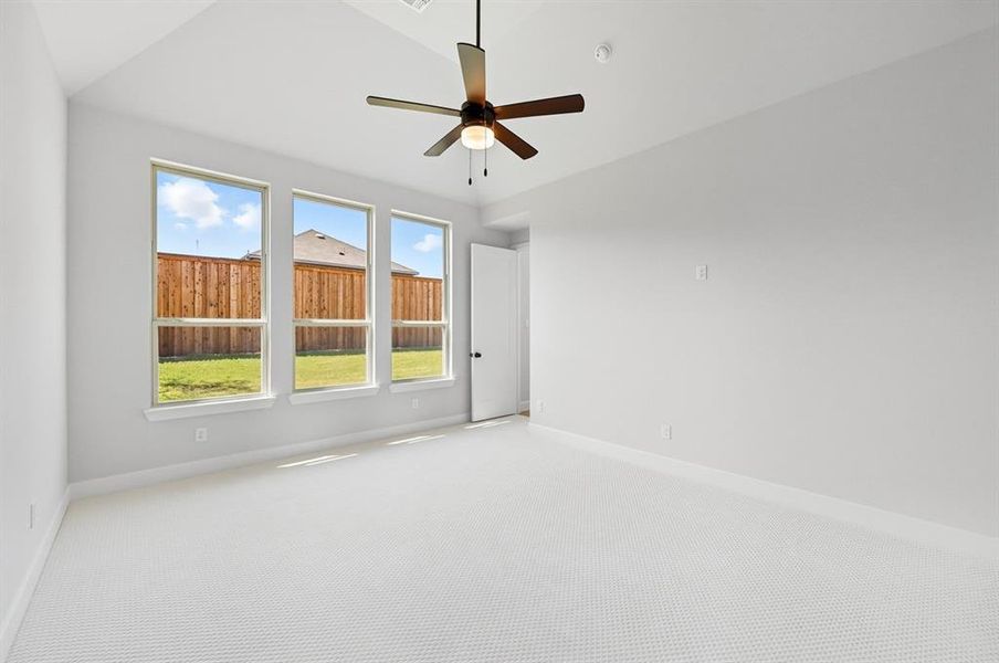 Carpeted spare room with lofted ceiling and a ceiling fan