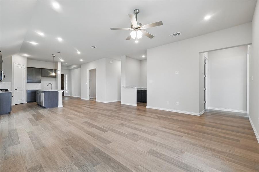 Unfurnished living room with ceiling fan, light wood-type flooring, baseboards, a sink, and recessed lighting Unfurnished living room with ceiling fan, light wood-type flooring, baseboards, a sink, and recessed lighting