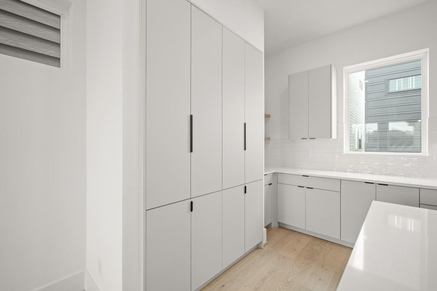 Storage is a true highlight of this kitchen, with pantry-depth cabinets with soft close doors and open shelving accented by under-cabinet lighting. These features provide both function and style, offering plenty of space to keep everything organized.