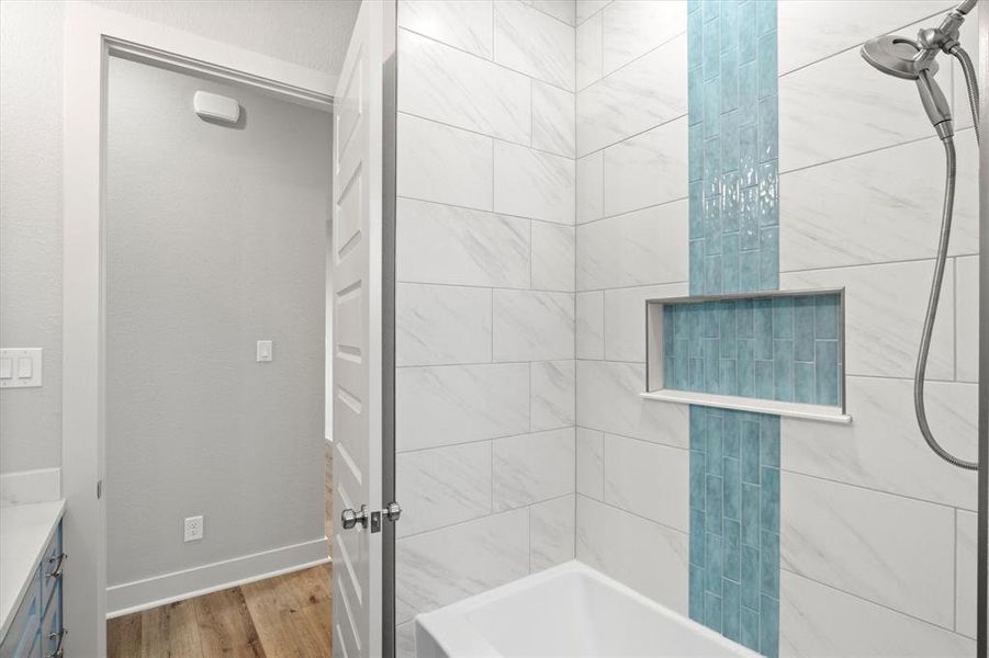 Full bath featuring wood finished floors, vanity, and tiled shower / bath combo Full bath featuring wood finished floors, vanity, and tiled shower / bath combo