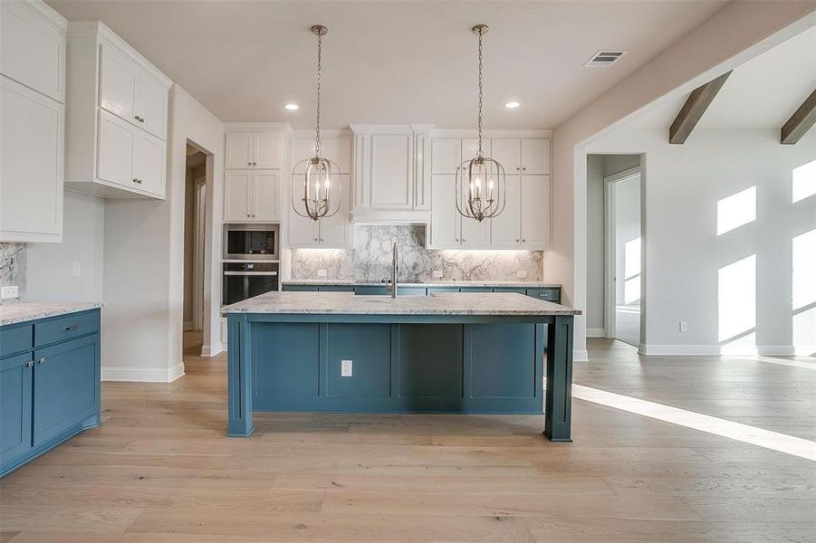 Kitchen featuring an island with sink, light hardwood / wood-style flooring, beamed ceiling, and stainless steel appliances