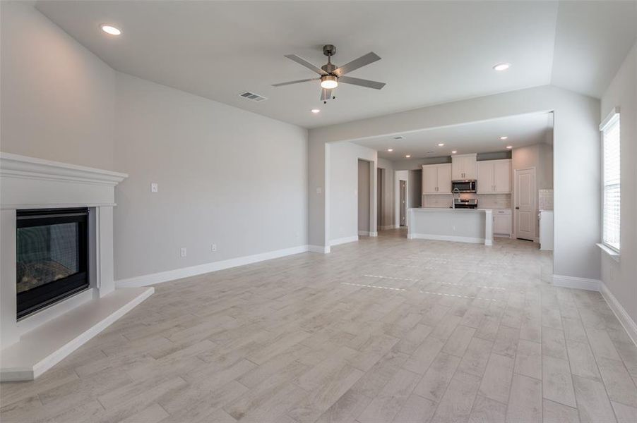 Unfurnished living room featuring ceiling fan, light hardwood / wood-style floors, and vaulted ceiling